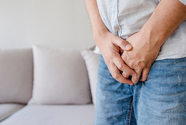下半身を両手で押さえる男性のイメージ