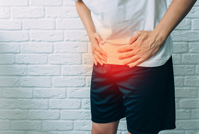 下半身を両手で押さえる男性のイメージ