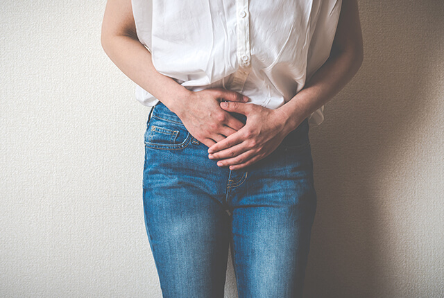 下半身を両手で押さえる女性のイメージ