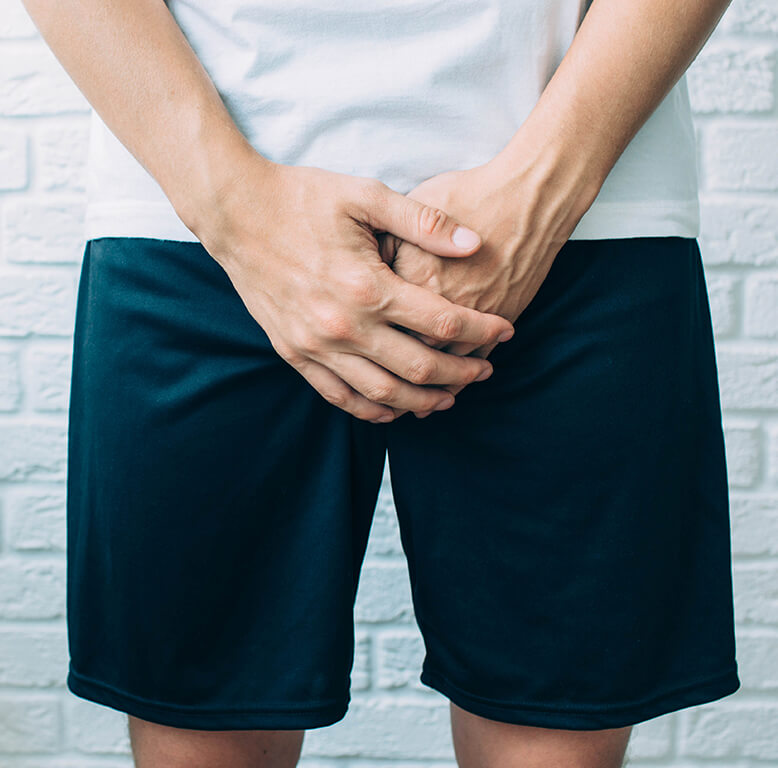 下半身を両手で押さえる男性のイメージ