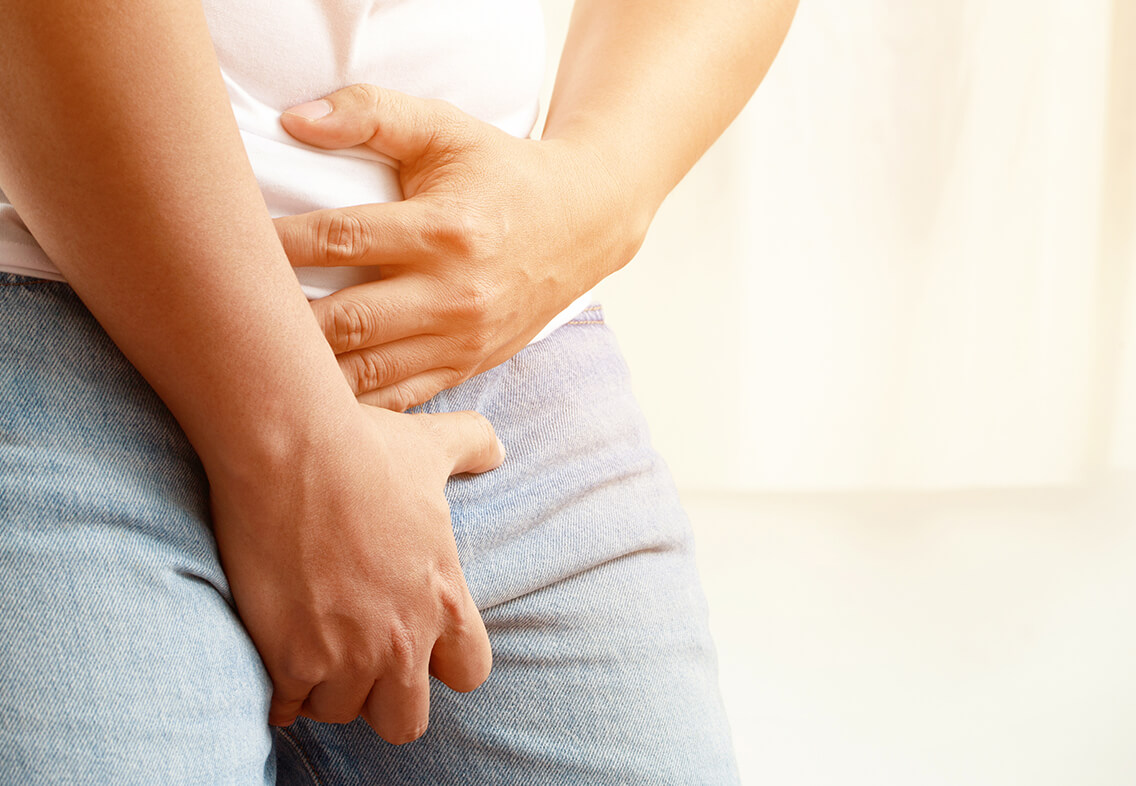 下半身を両手で押さえる男性のイメージ